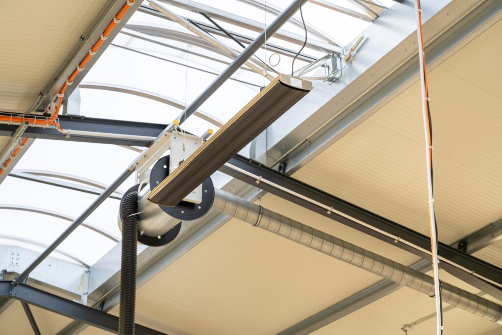Fahrzeugprüfhalle heizen: Flächenspeicherheizung im Büro, Dunkelstrahler in der Halle Elektrischer Dunkelstrahler über der Fahrspur einer Prüfhalle