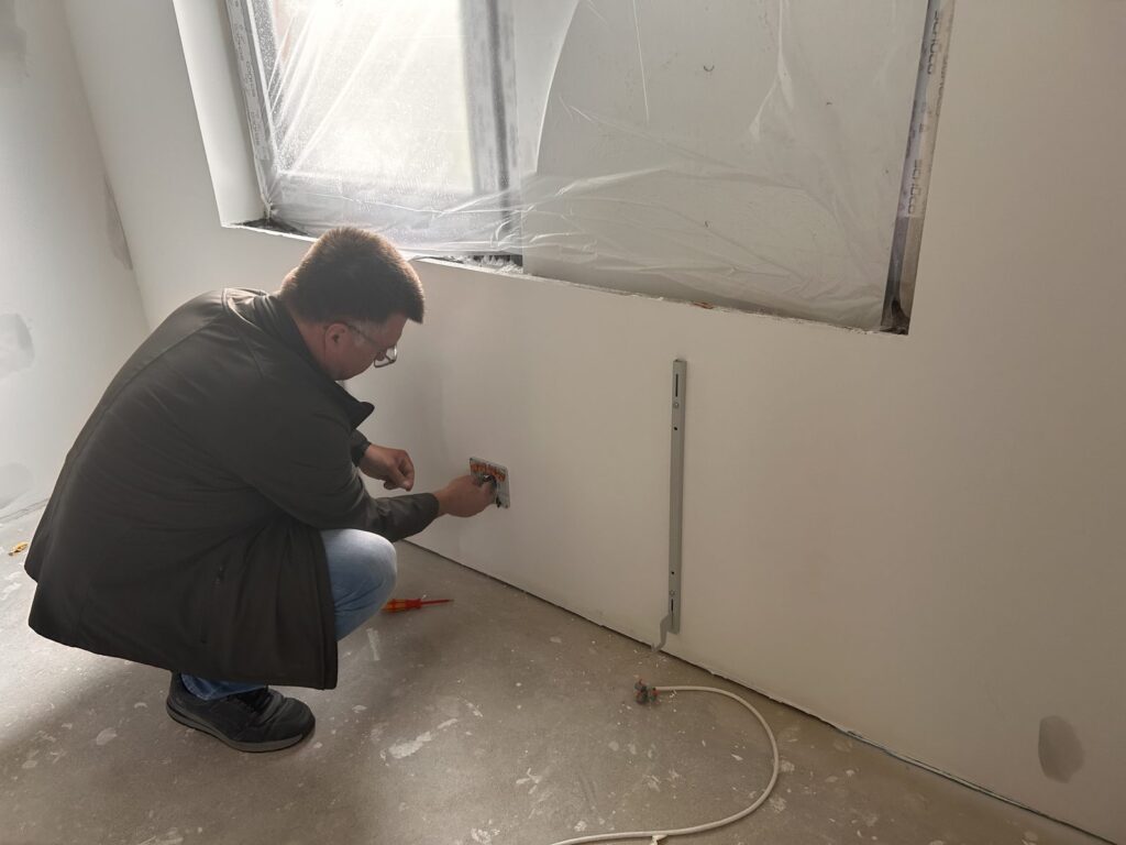 Elektroinstallateur beim Anschluss der Zuleitung an die Flächenspeicherheizung vor der Montage